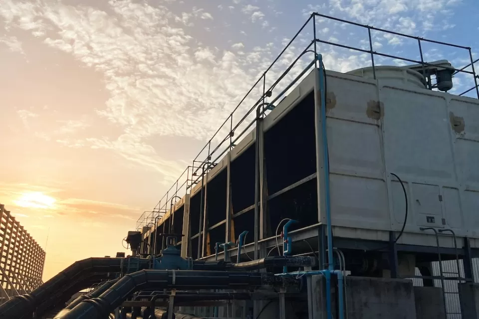Cooling tower on data center building roof against twilight sky.